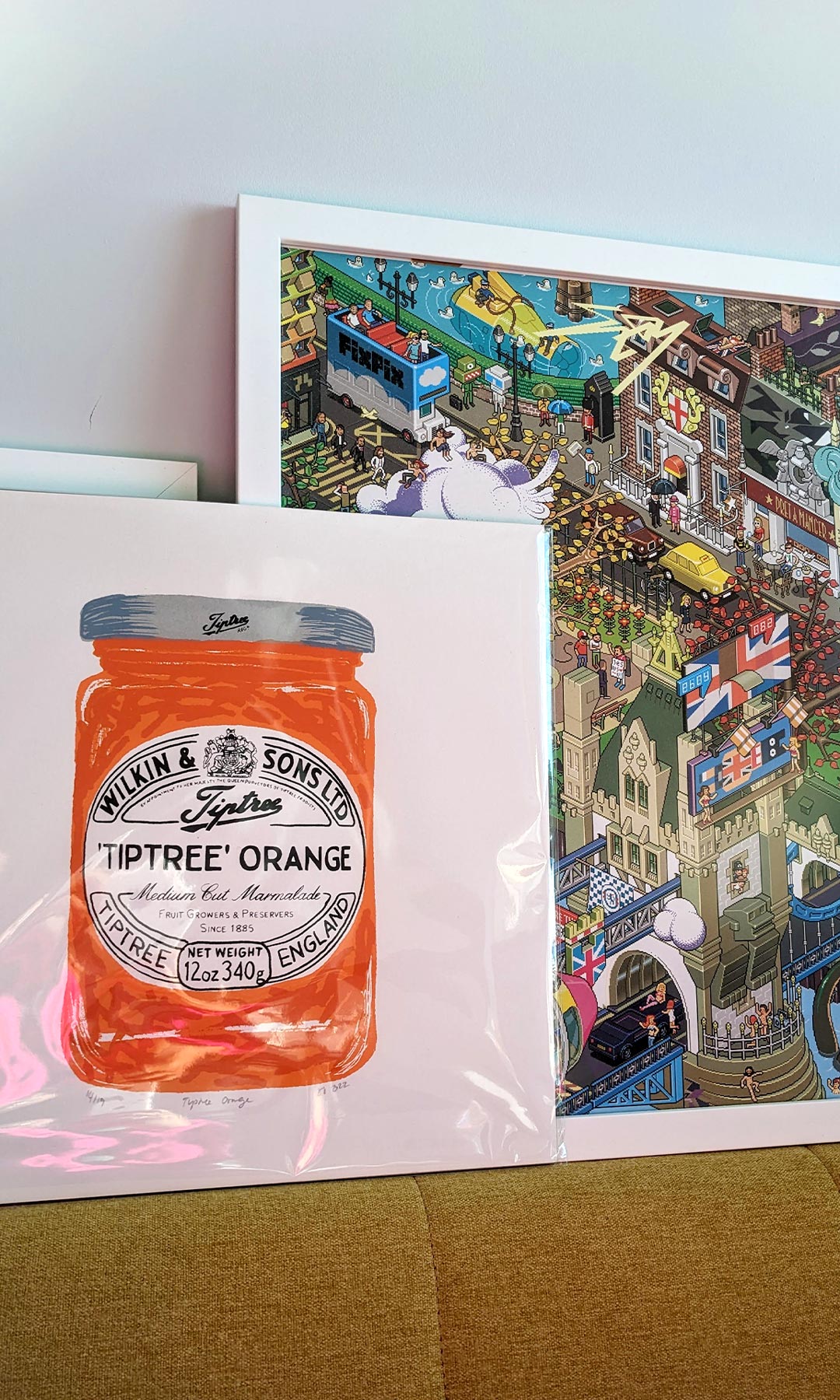 Art prints on a wall at the Yoco Studio, London. A Tiptree orange marmalade illustration by DESIGN SMITH STUDIO, and a pixelated London print by eBoy.